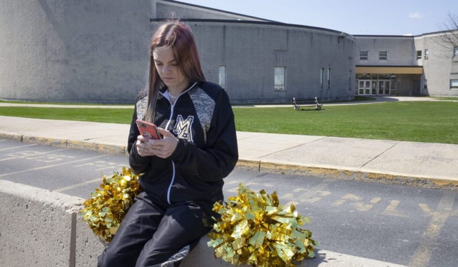 Brandi Levy is seen here wearing her former cheerleading outfit as she looks at her phone while outside Mahanoy Area High School in Mahanoy, FL.